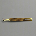 Gold-colored eyelash extension tweezers on a gray background