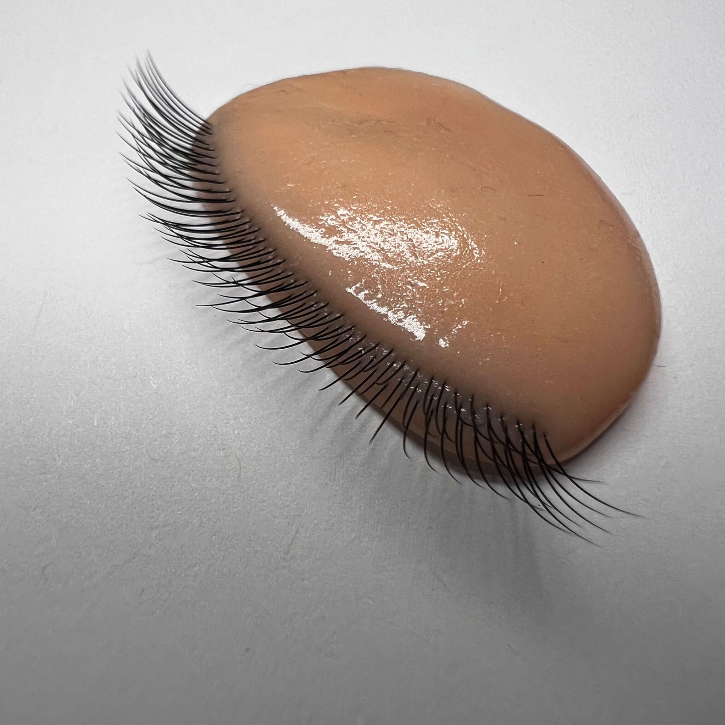 False eyelashes on a brown silicone applicator against a gray background