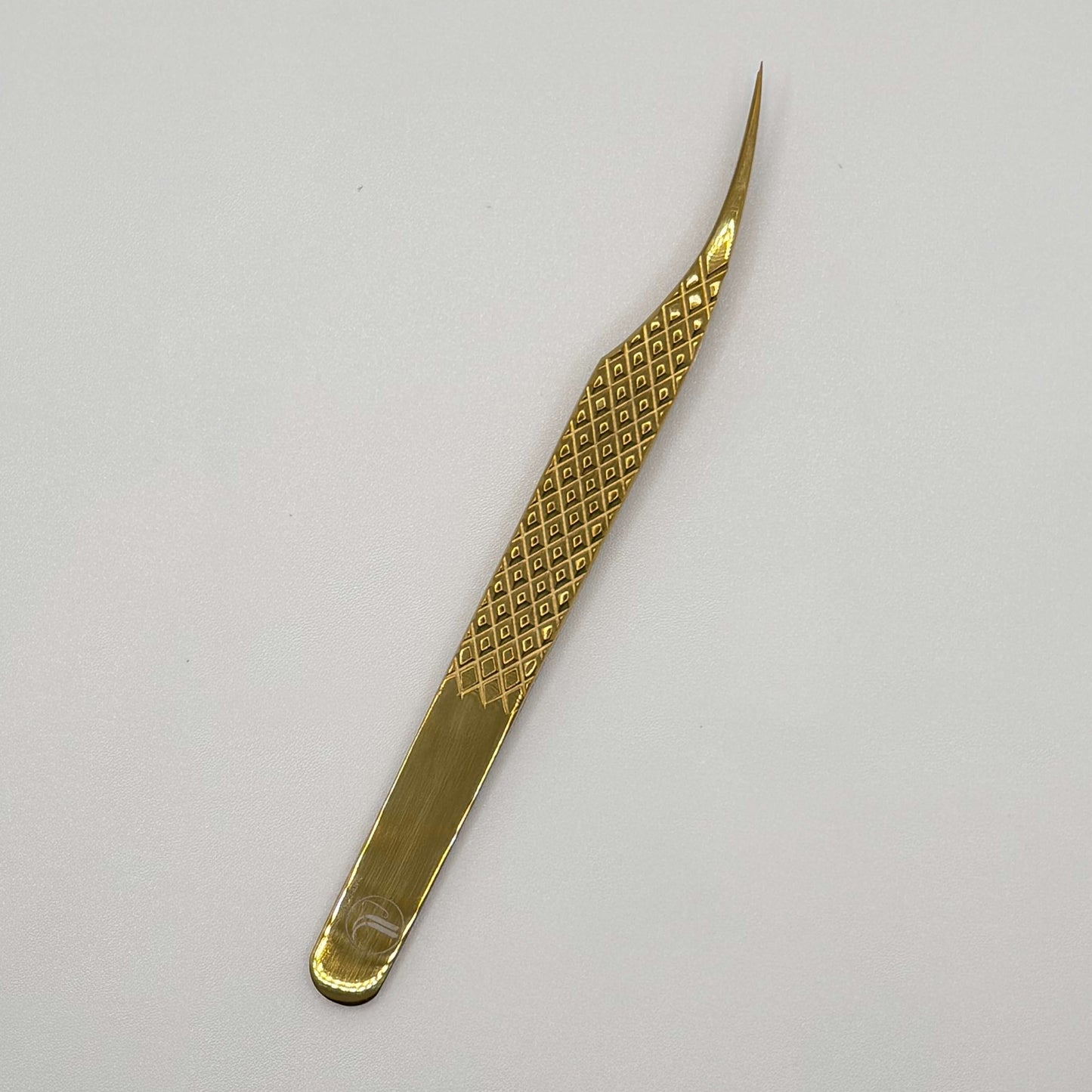 Gold-colored tweezers on a white background with top down view