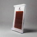A tray of copper red cashmere eyelashes presented in a clear plastic case with a white background, showcasing the product's packaging and design.