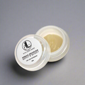 A small open jar of cream remover for eyelash extensions with a label on the lid. The cream is intended for lash tech use and is presented on a neutral background.