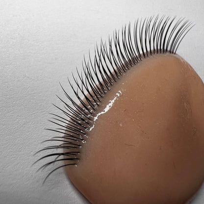 False eyelashes at an angle on a brown silicone surface with a light gray background
