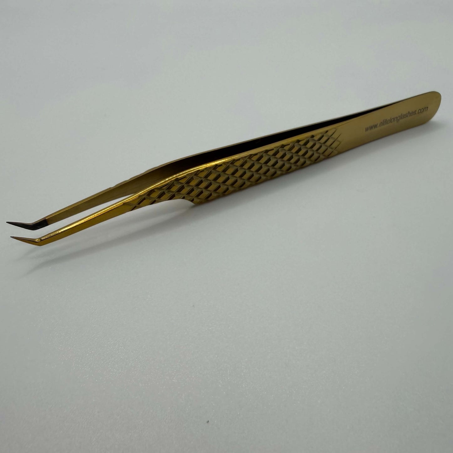 Gold-colored tweezers on a white background