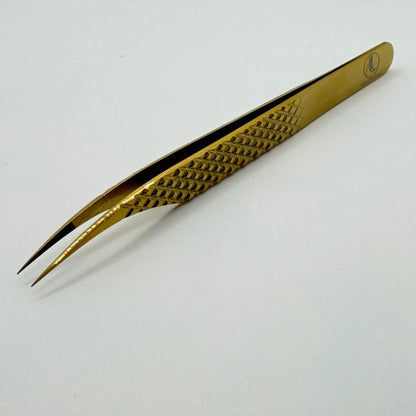 Gold-colored tweezers on a white background