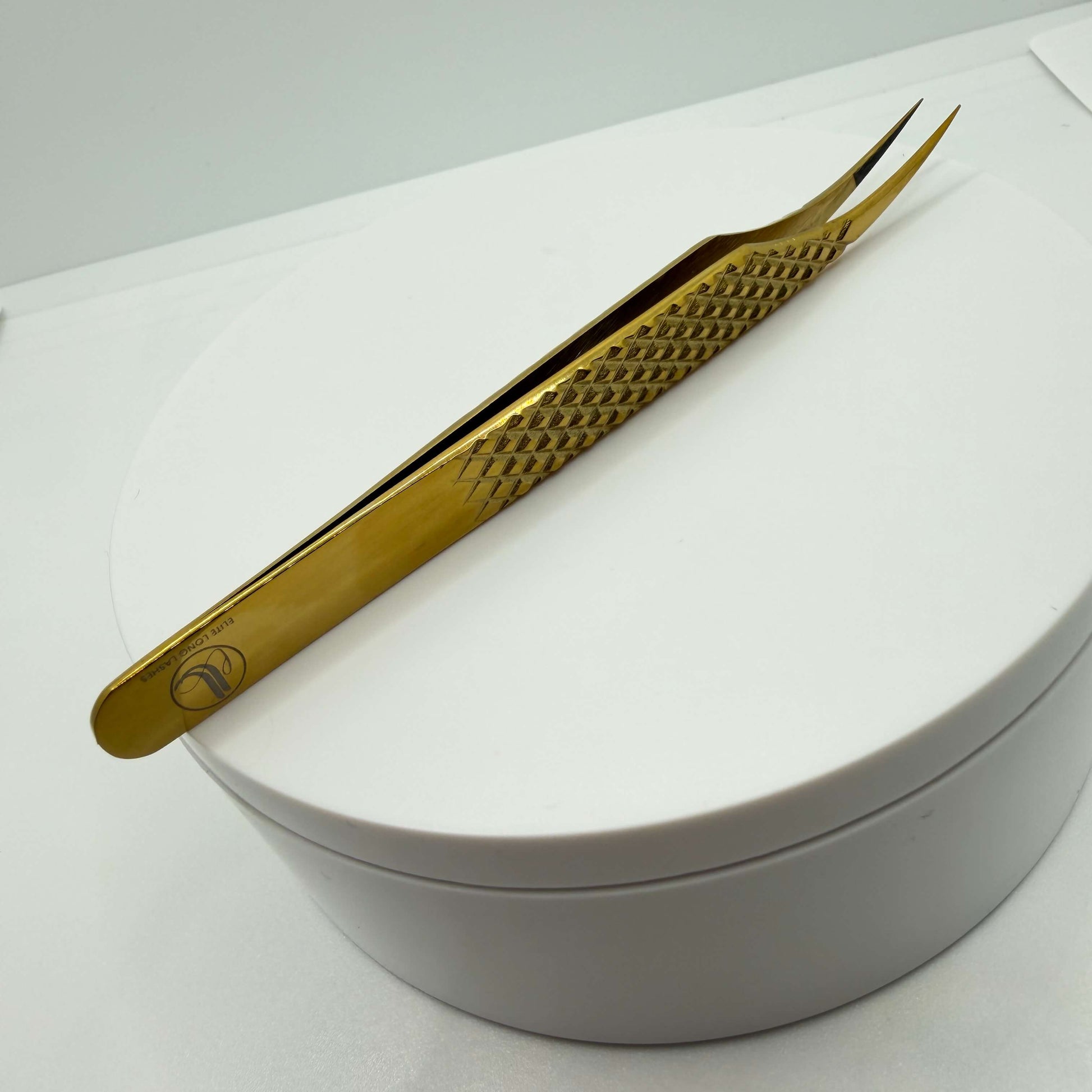 Gold-colored tweezers on a white surface