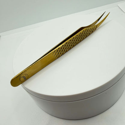 Gold-colored tweezers on a white surface