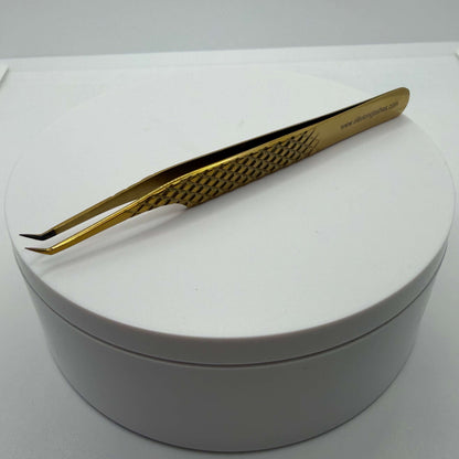 Gold tweezers on a white round container with a white background