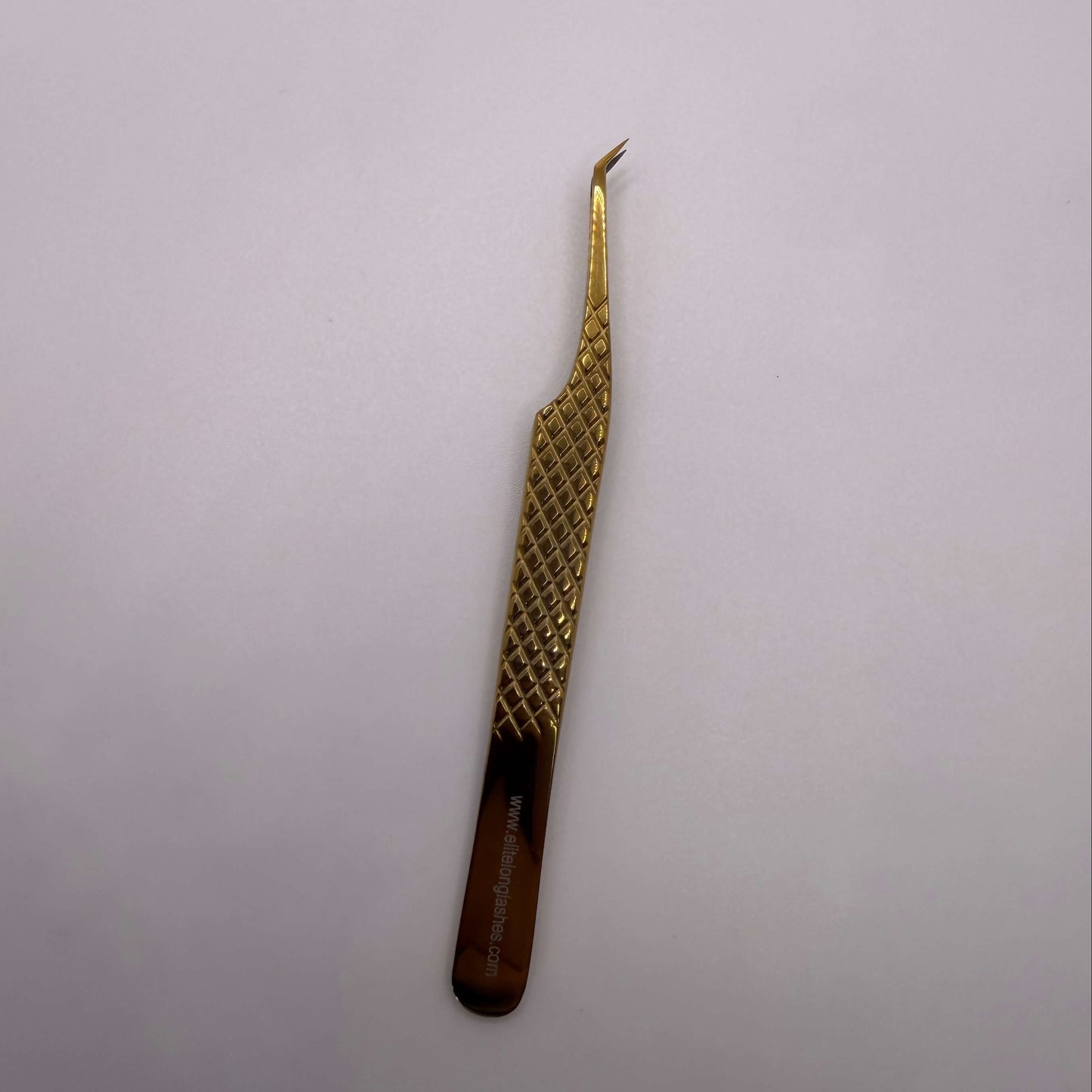 Gold tweezers with a textured handle on a light gray background