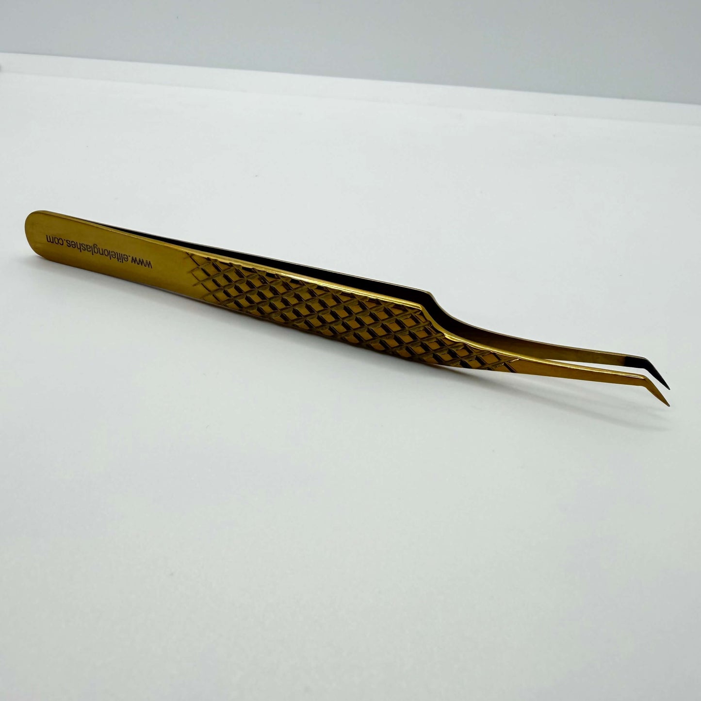 Gold tweezers with a textured handle on a white background