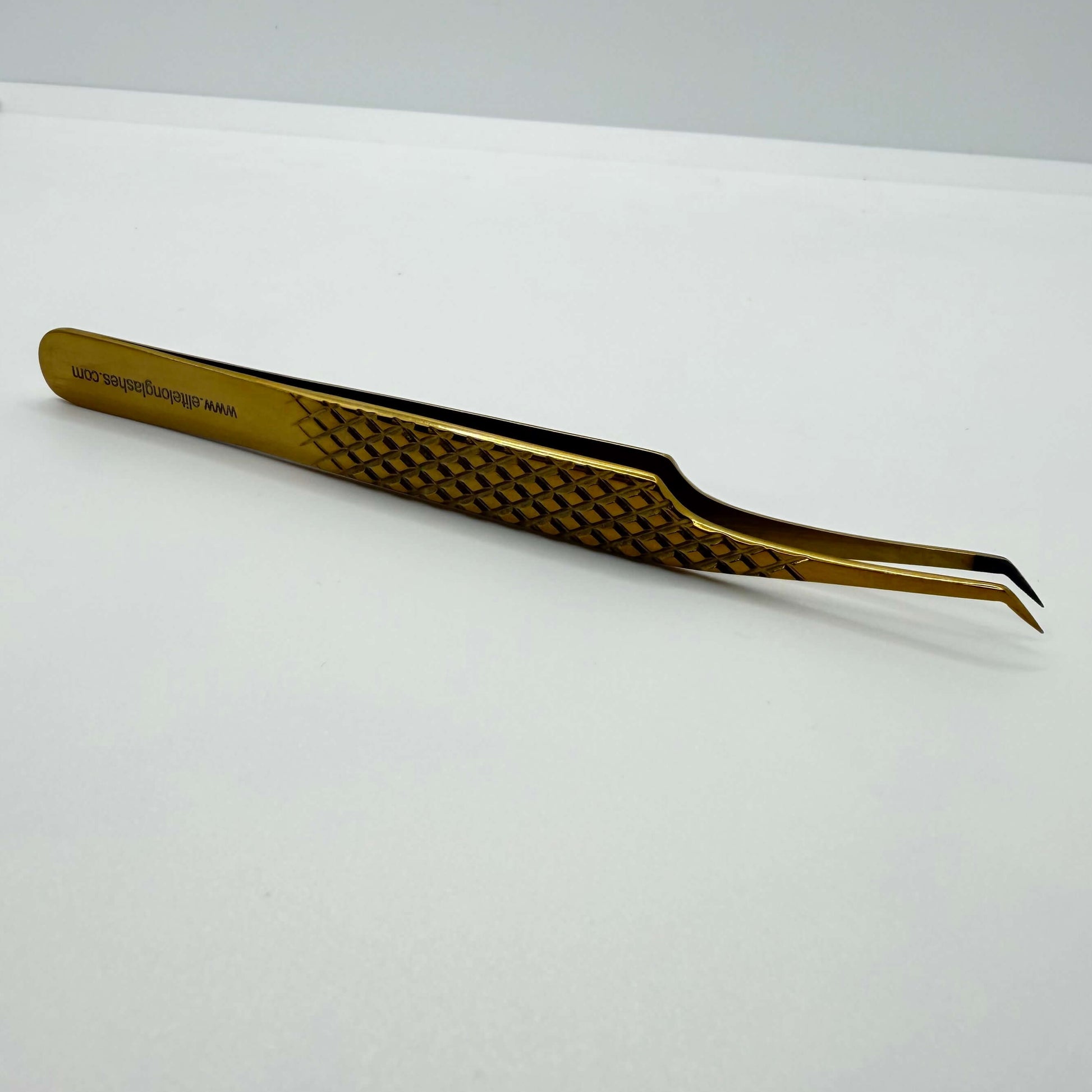 Gold tweezers with a textured handle on a white background