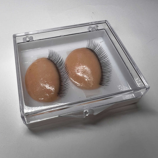 Pair of false eyelashes on brown silicone in clear box on a light gray background